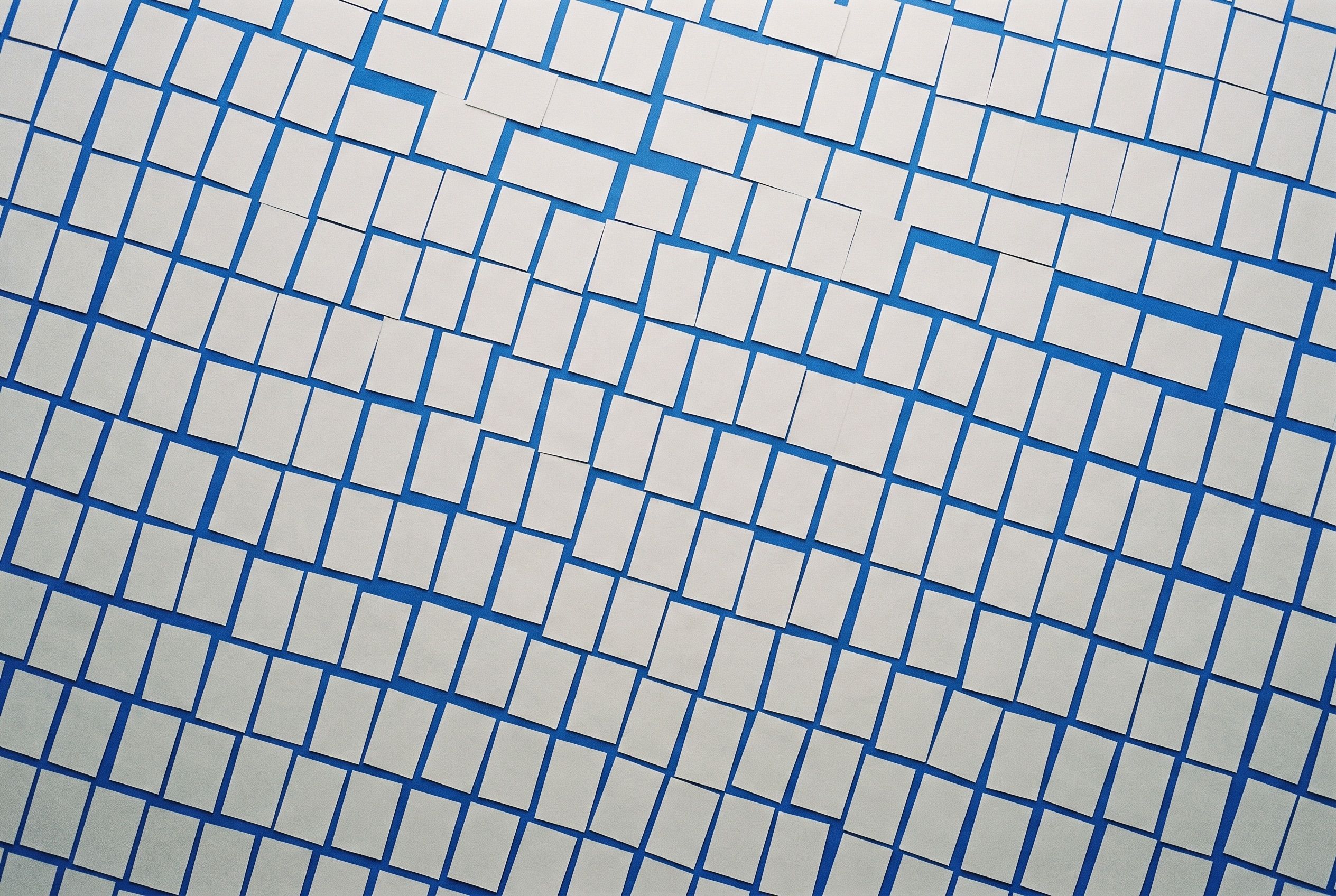 Hundreds of pale grey cards laid in a loose grid over a cobalt blue surface, seen from directly above.