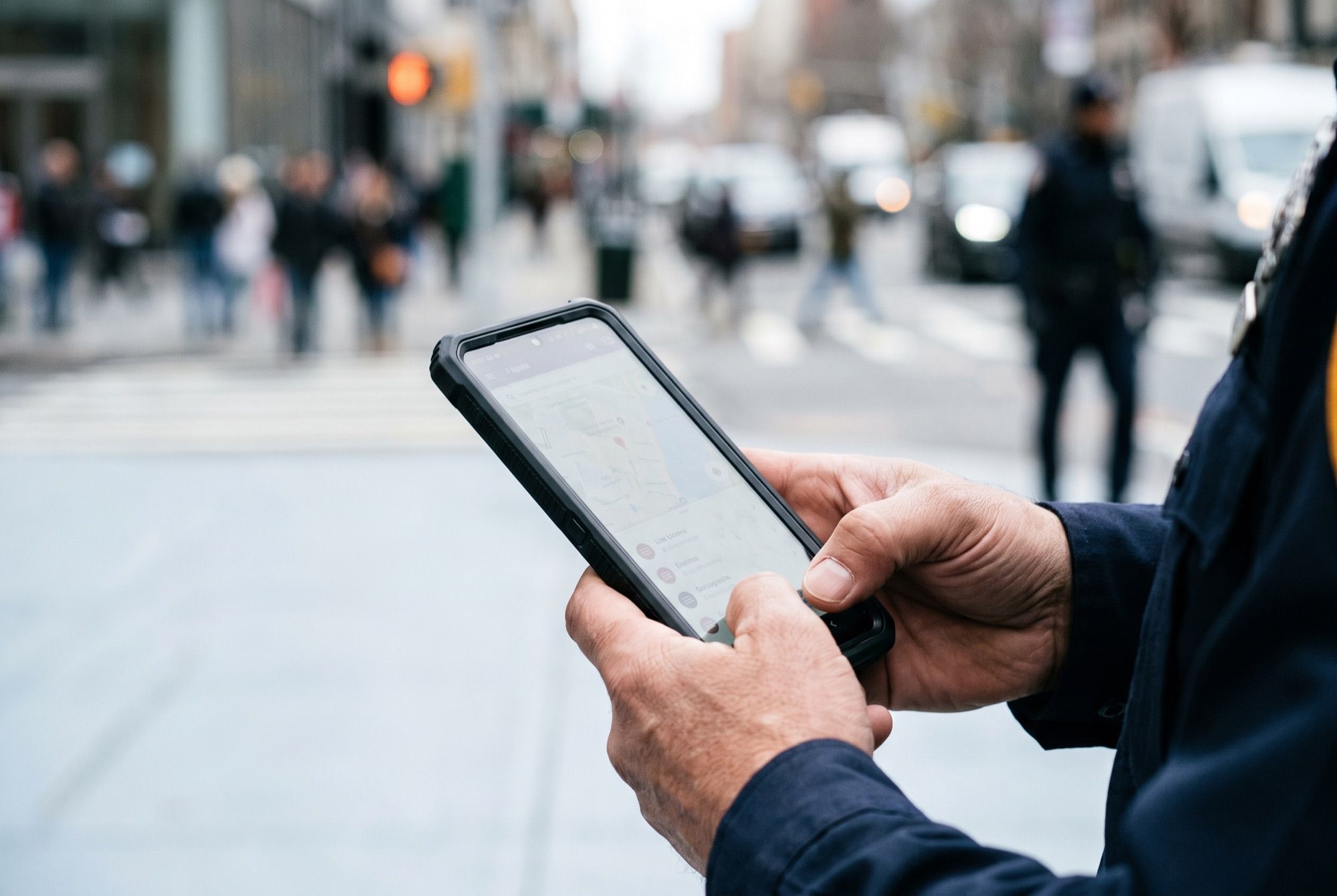 An officer checking a map and incident information on a rugged smartphone in the field